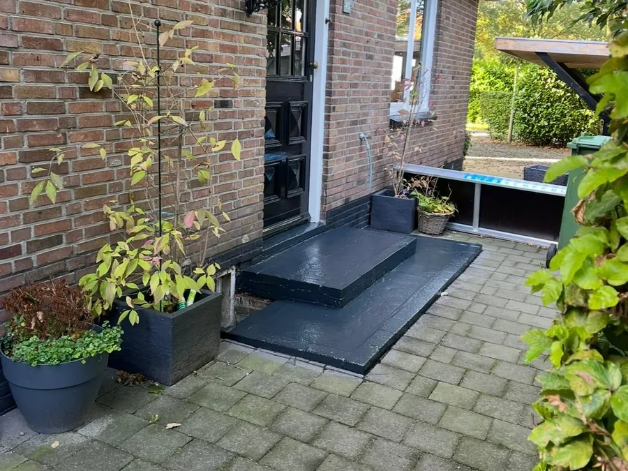 Entree van een woning met zwart geschilderde voordeur, kozijnen en stoep