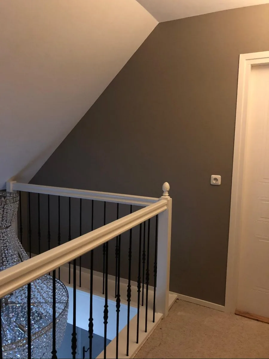 Overloop met een warme taupe wand en een witte trapleuning